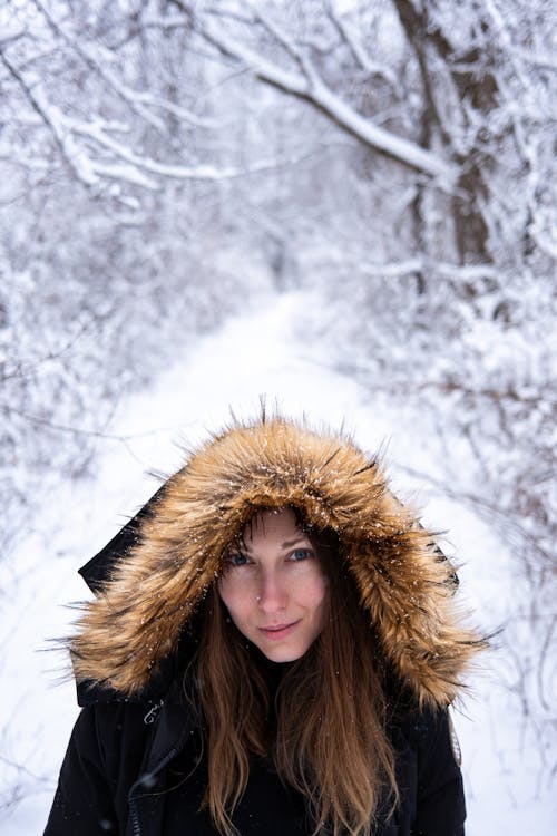 Woman in Jacket with Hood in Forest in Winter