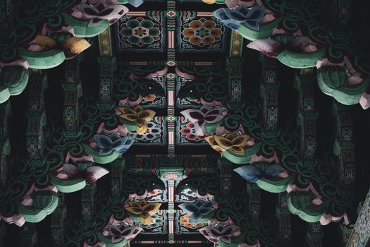 A vibrant, detailed carved and painted wooden ceiling with floral designs