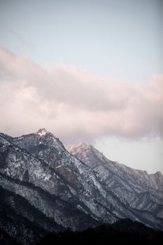 Serene wintery mountain scene with majestic snowy peaks beneath a cloudy sky, ideal for nature and travel imagery.