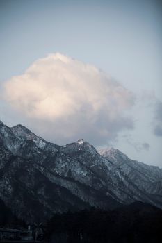 Snow-capped mountains with a large cloud, perfect for travel inspiration and nature lovers.