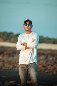 Confident man with sunglasses and arms crossed in an outdoor setting