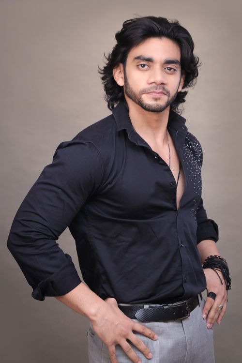 Free A confident man posing in a fashionable black shirt and gray pants, suitable for fashion and portrait themes. Stock Photo