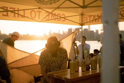 People Standing at a Waterfront Bar under a Tent
