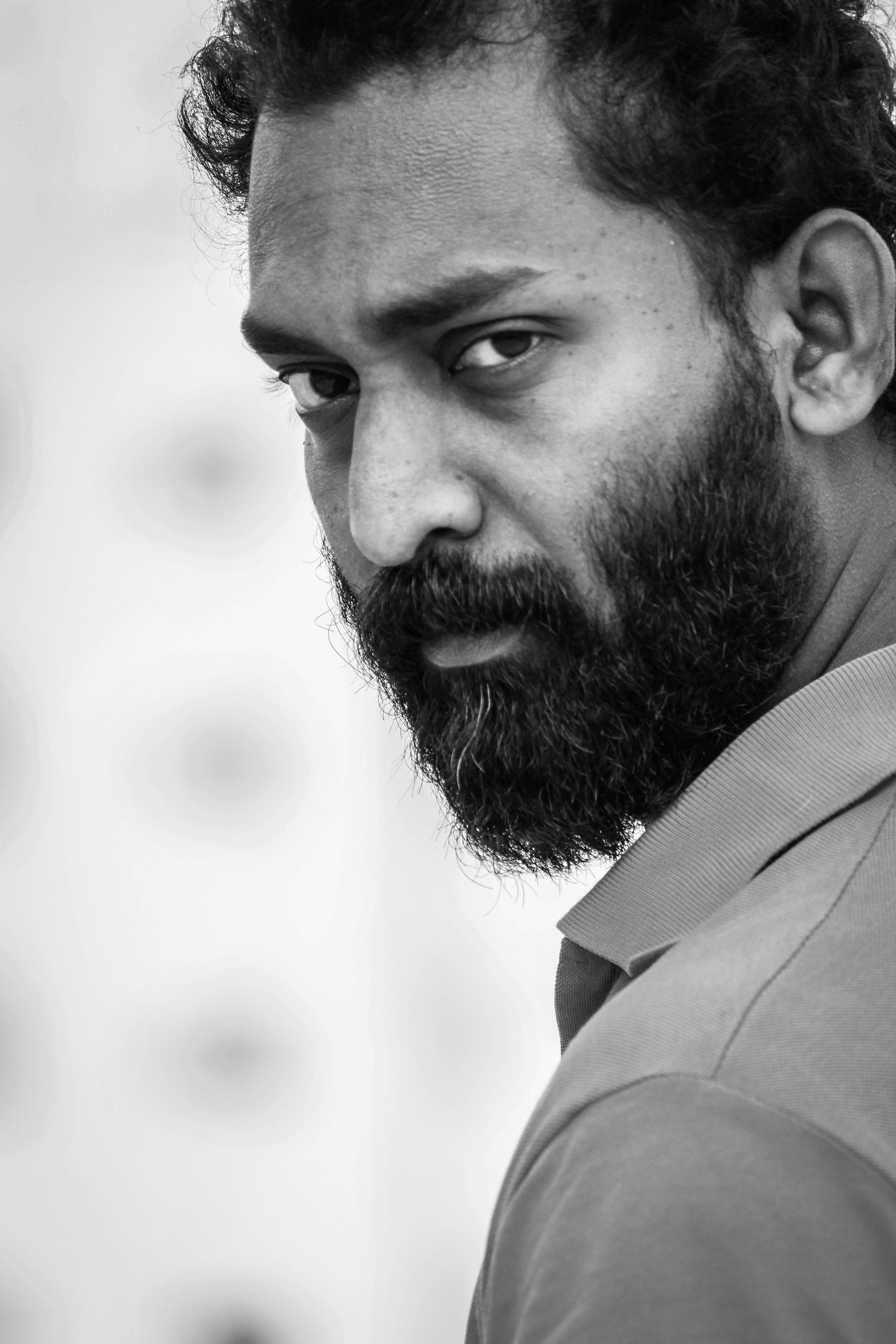A striking black and white portrait of a bearded man with a moody expression.