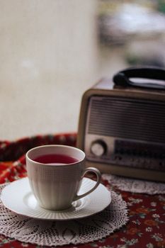 A charming still life of a white cup of fruit tea next to a vintage radio, exuding retro vibes.