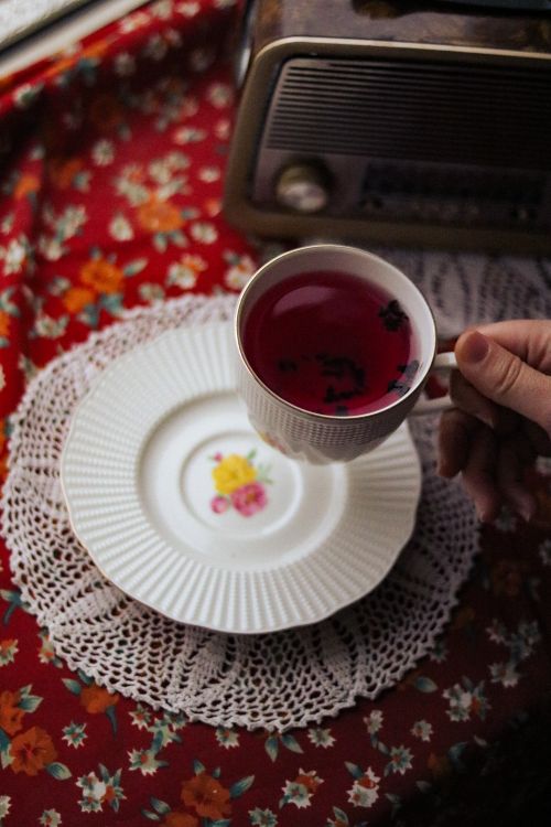 Free A hand holding a cup of fruit tea beside a vintage radio in a retro setting. Stock Photo