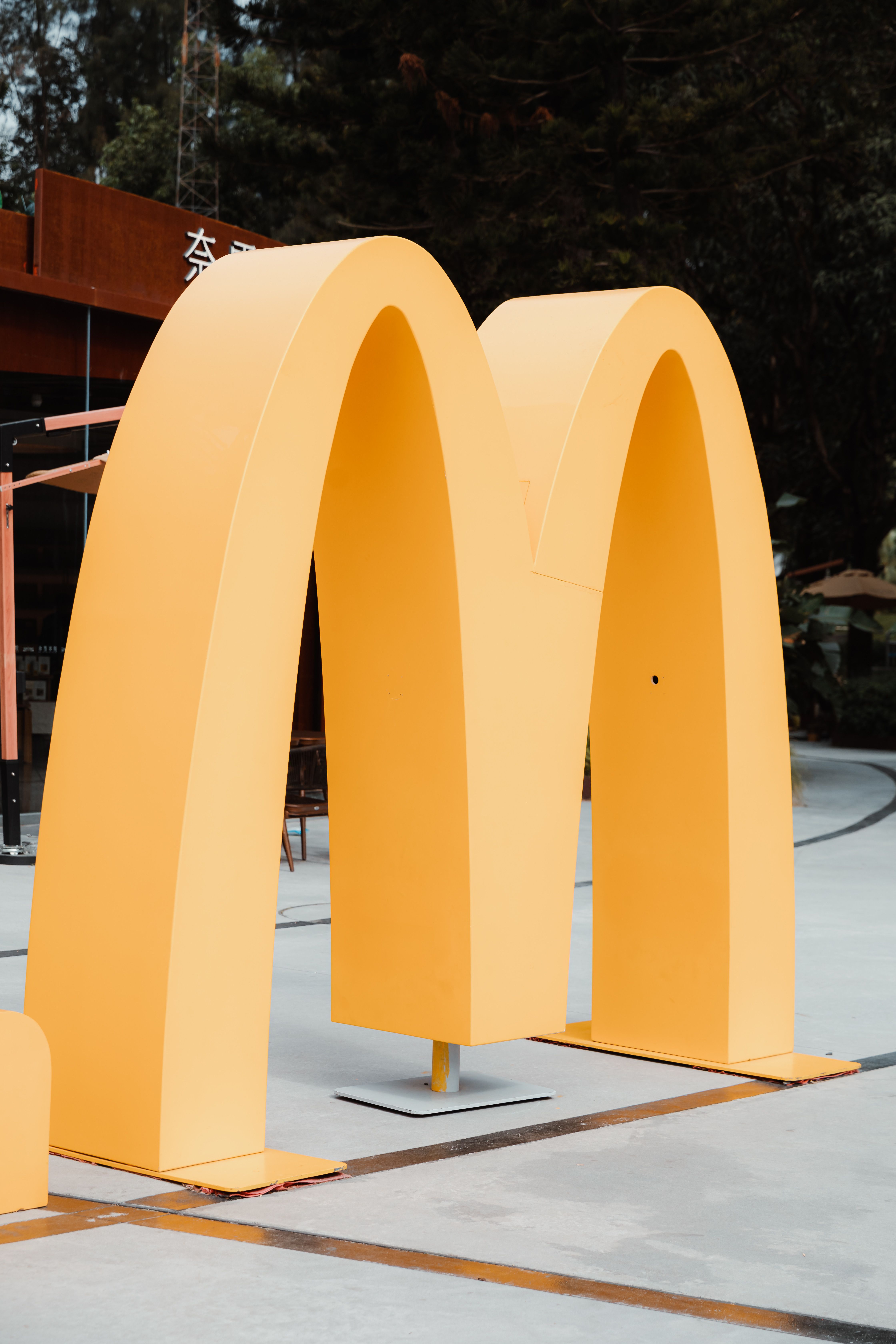 Close-up of a large yellow McDonald's arch in an outdoor setting, symbolizing fast food culture.