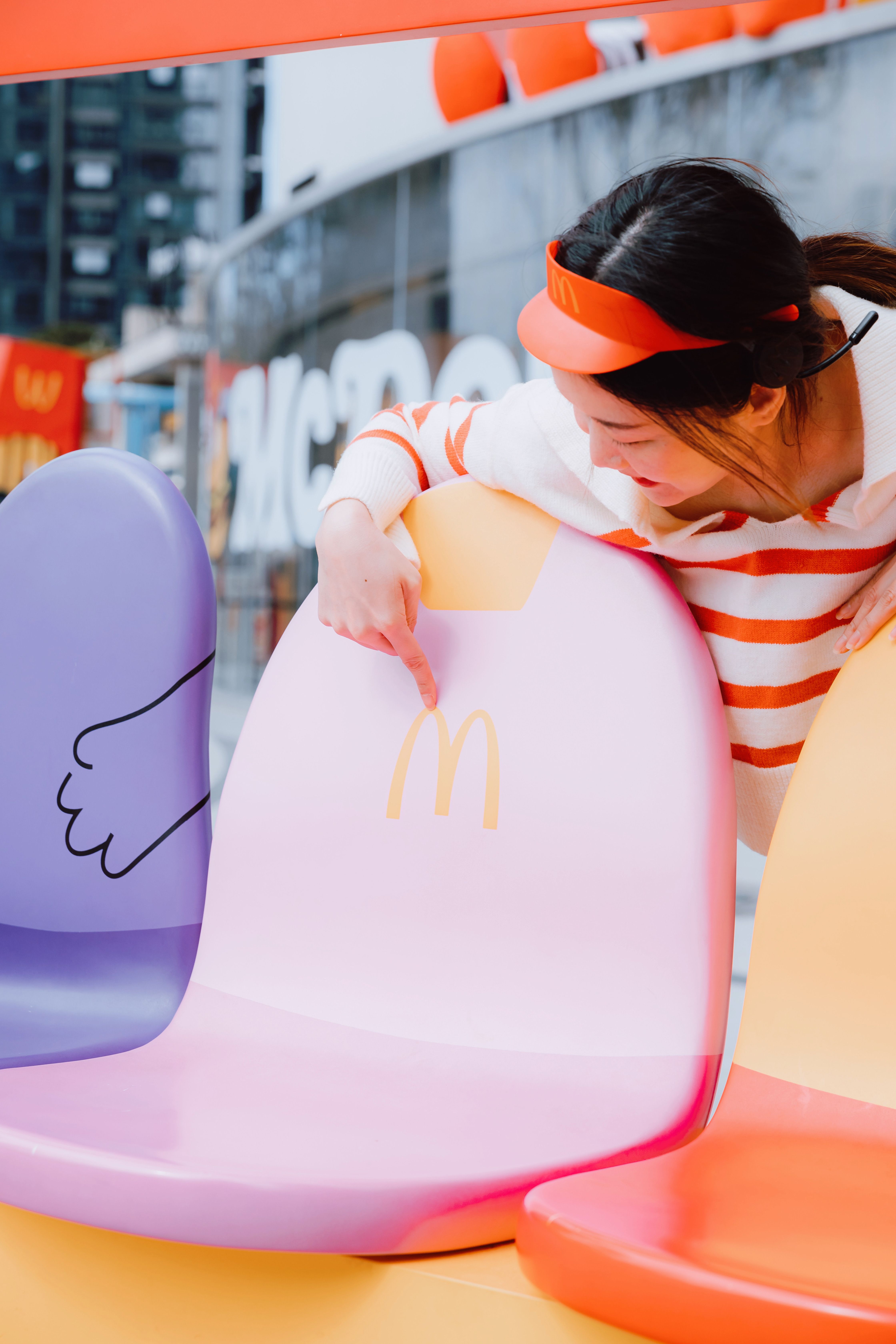 Woman in Cap Pointing on Seat with McDonalds Logo · Free Stock Photo