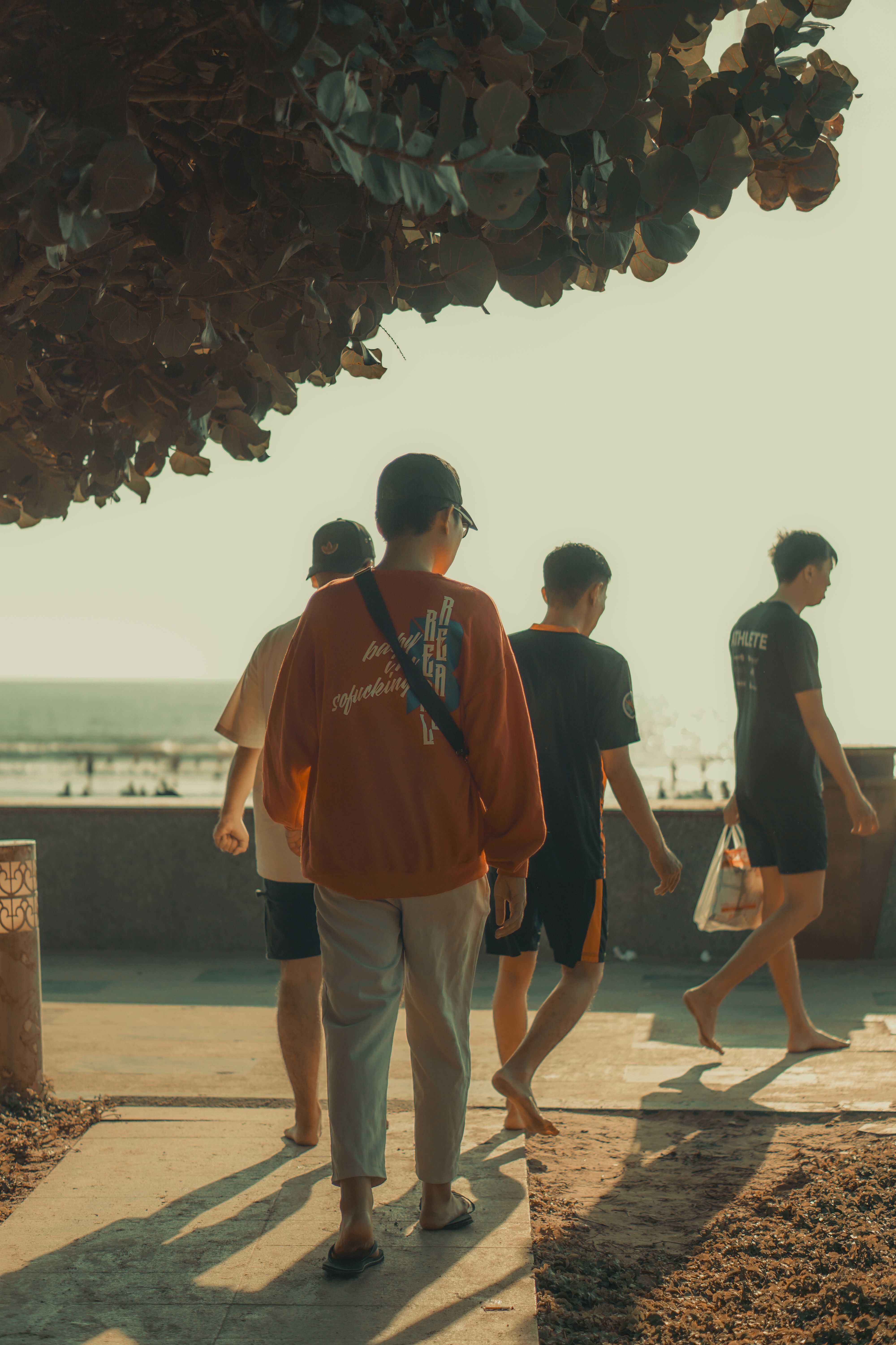 Four young adults walk along the beach promenade in Vũng Tàu, Vietnam, under shade.