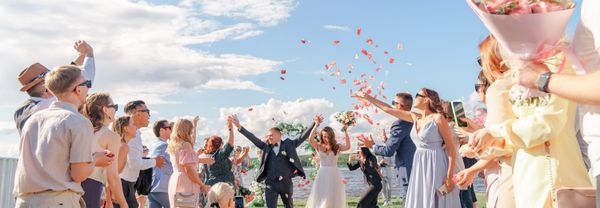 Wedding guests throwing confetti as the couple walk through