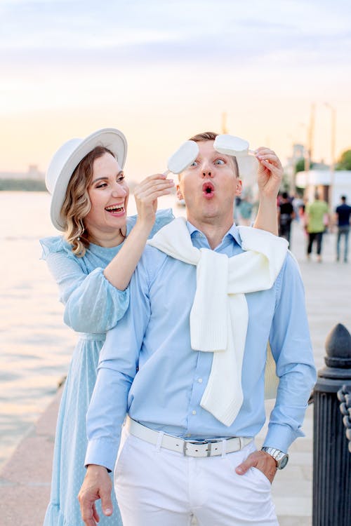 Smiling Woman Holding Ice Creams over Man in Blue Shirt