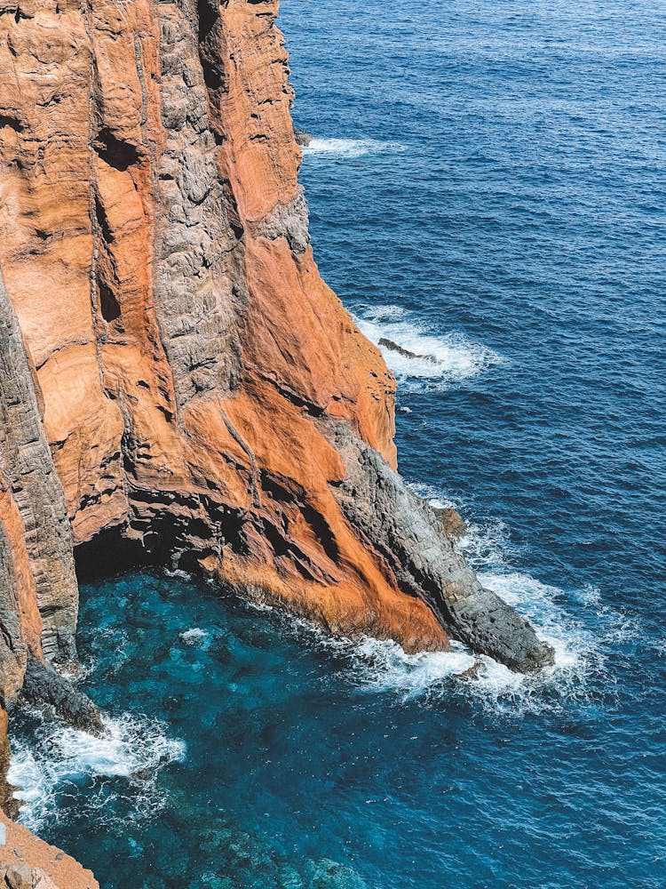 Ocean Waves Crushing On A Steep Red Rock Cliff 