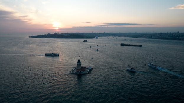 Stunning aerial view of Istanbul's Maiden's Tower at sunset with boats gliding on the Bosphorus.