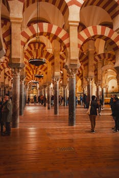 The iconic arches of the Mosque-Cathedral in Córdoba with visitors exploring the historical landmark.
