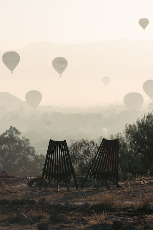 Chairs Overlooking Hot Air Balloons Flying over Desert in Mexico