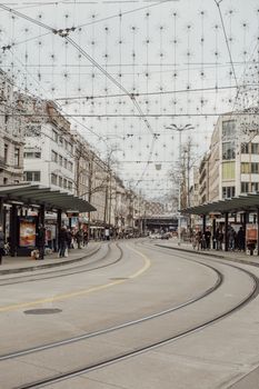 Bustling tram stop in central Zurich, showcasing urban life with a winter backdrop.