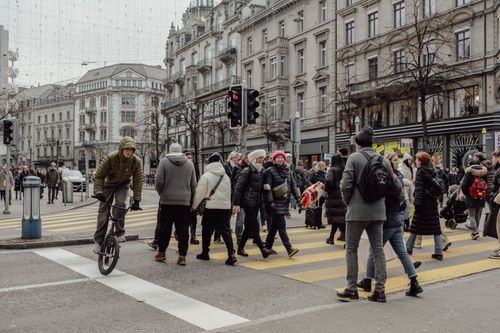 Free Crowded street scene in Zurich with pedestrians crossing and a cyclist in a lively urban setting. Stock Photo