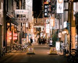 大阪购物街的繁华夜景中，有照明的标志和来往的行人