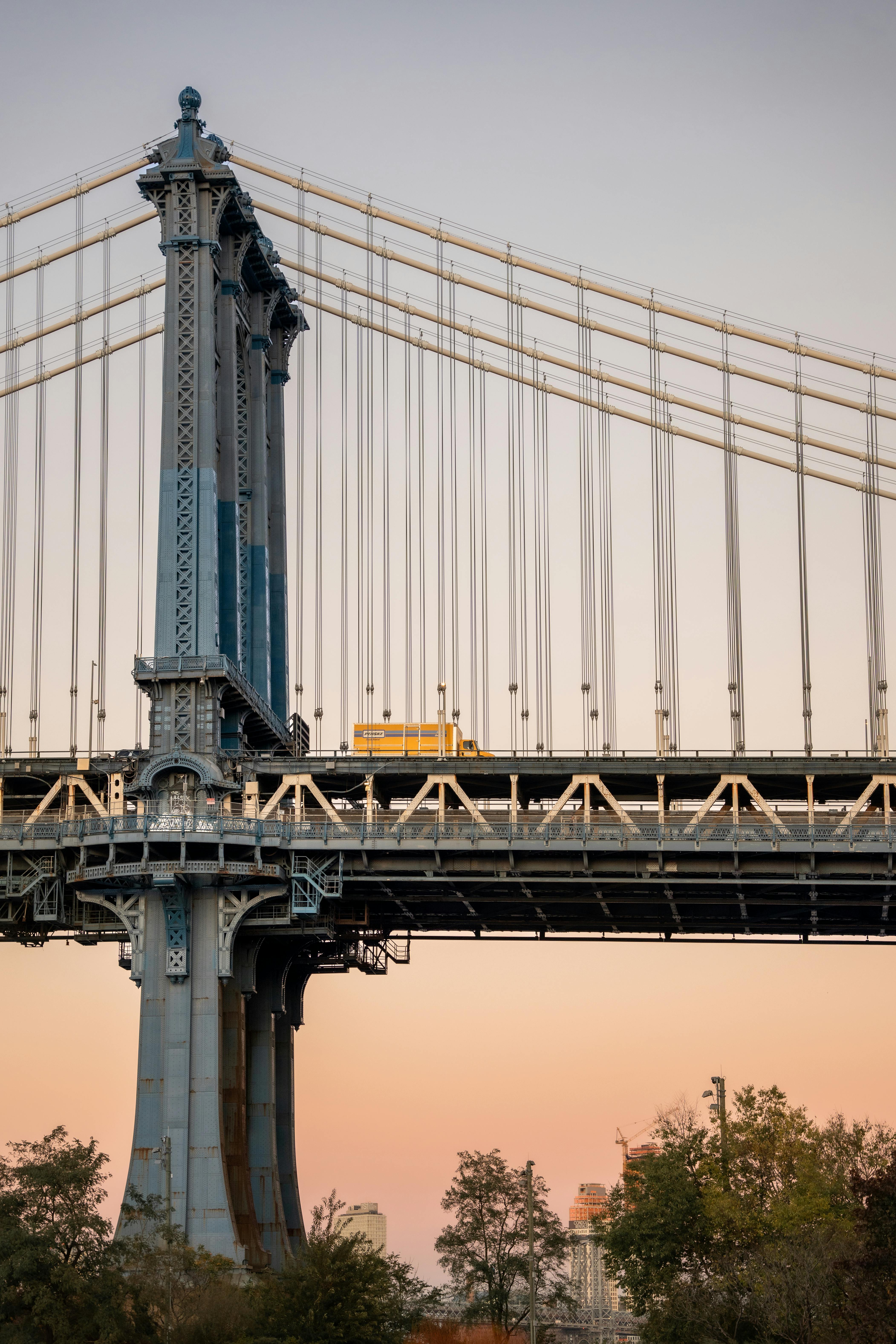 A vertical shot of the Manhattan Bridge at sunset with a bus crossing it in New York City.