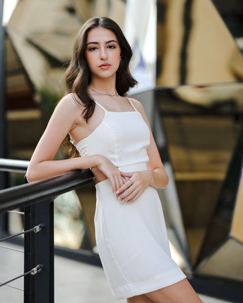 Free Stylish brunette woman posing in a chic white dress. Urban fashion vibe. Stock Photo