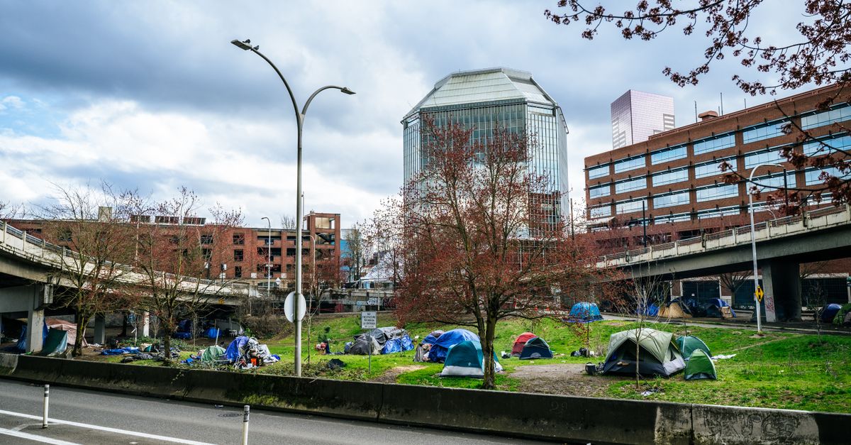 Colorful tents set up in a green area of downtown Portland, Oregon, highlight urban social issues.
