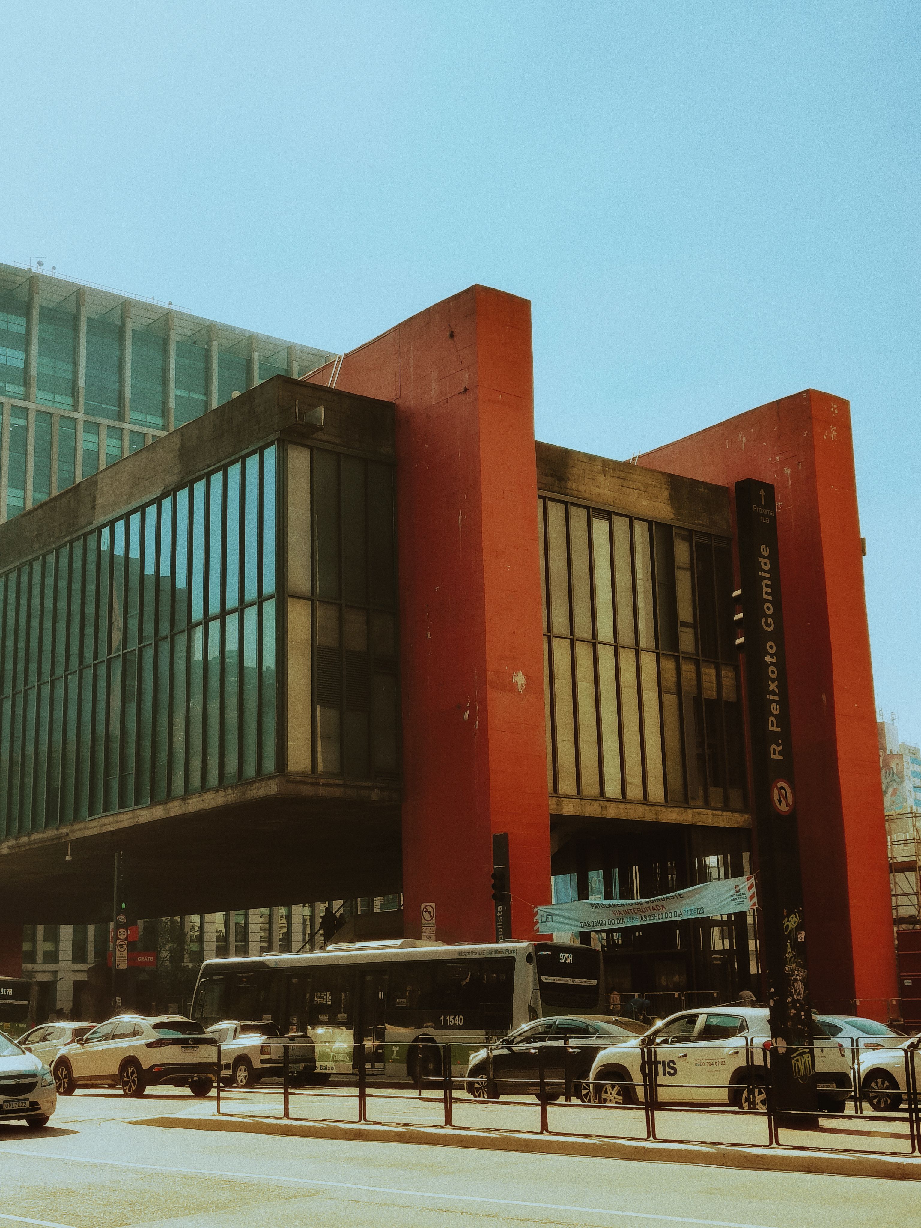 Modern building in São Paulo with cars and buses in the foreground, sunny day.