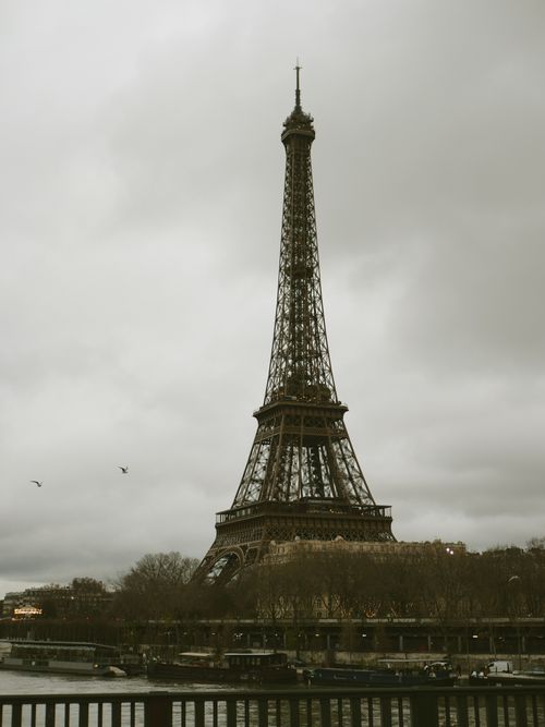Free Majestic Eiffel Tower standing tall on a cloudy day in Paris, France, iconic cityscape. Stock Photo