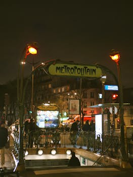 Iconic Paris metro entrance at night with an Art Nouveau design, inviting travelers to explore the city.