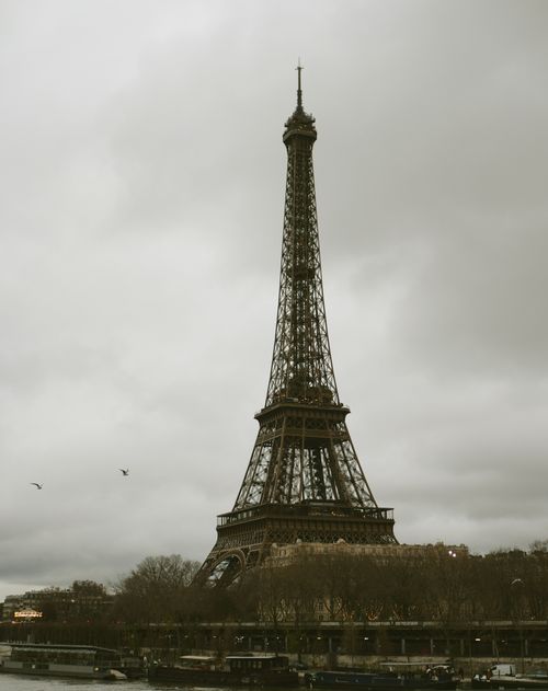 Free Iconic Eiffel Tower in Paris seen against a cloudy backdrop, capturing the essence of French architecture. Stock Photo