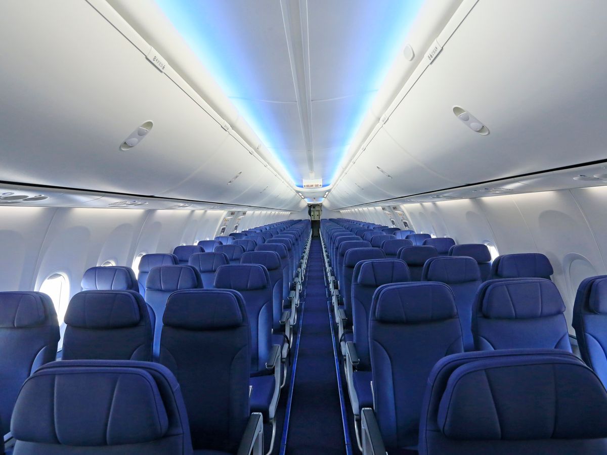 Rows of empty blue aircraft seats viewed down the cabin aisle