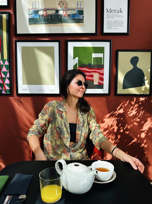 Young Woman in Sunglasses Sitting at a Table in a Cafe 