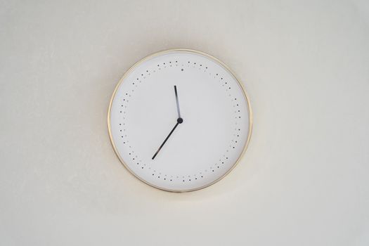A minimalist design wall clock with a gold rim and no numbers on a neutral background.