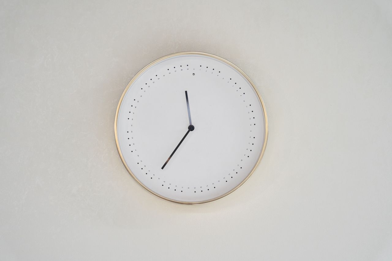 a minimalist design wall clock with a gold rim and no numbers on a neu