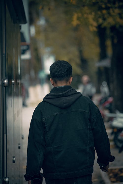 Back View of a Man Walking on a Sidewalk in City 