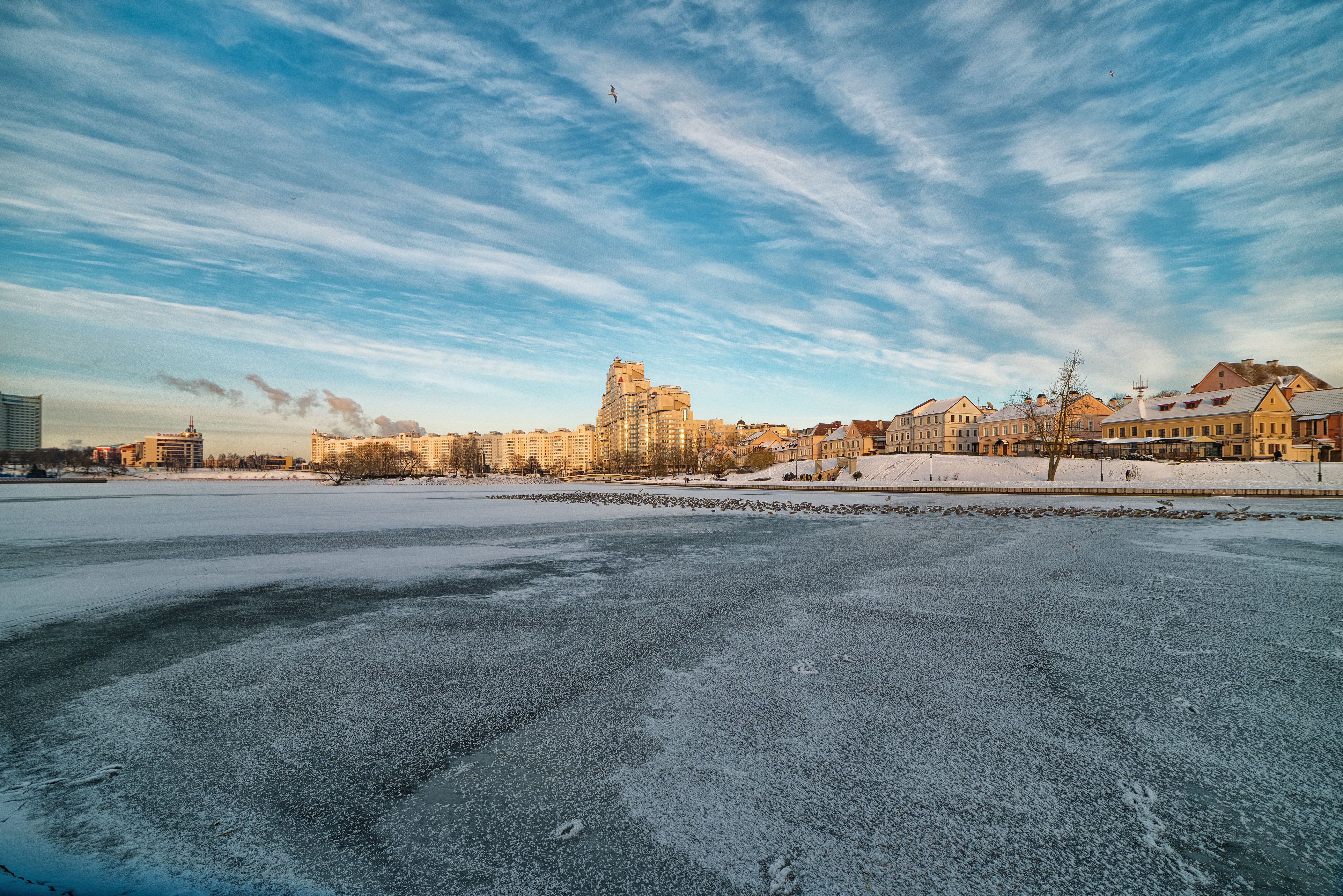 A serene winter view of Minsk with a frozen lake and clear sky.