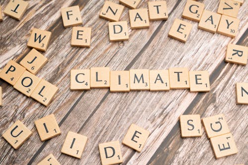 Free Wooden Scrabble tiles arranged to spell 'CLIMATE' on a wooden surface. Stock Photo
