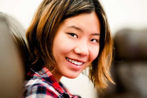 Free Close-up portrait of a smiling young woman wearing a plaid shirt indoors. Stock Photo