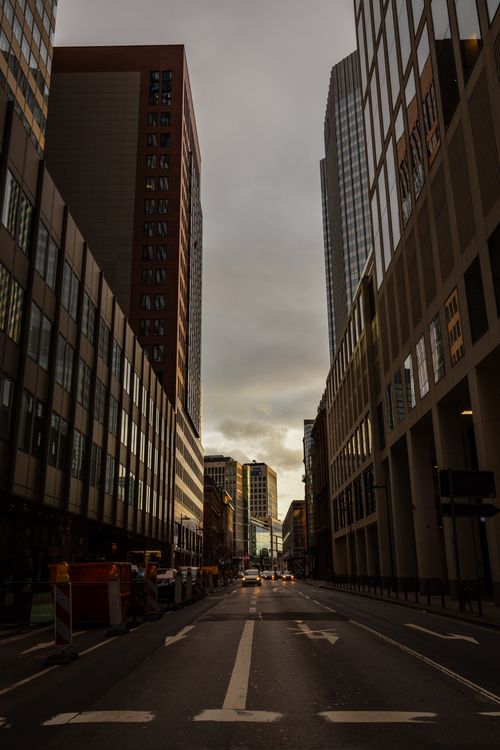 Free Captivating view of an empty city street surrounded by tall buildings during sunset. Stock Photo
