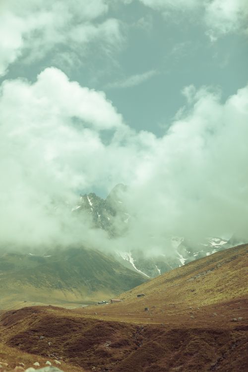 Free A breathtaking view of mist-covered mountains and rolling hills on a cloudy day. Stock Photo
