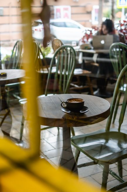 A warm coffee shop interior featuring a cappuccino on a rustic table, inviting atmosphere with natural light. - 7 Must-Visit Coffee Shops and Cafes in Bridgetown