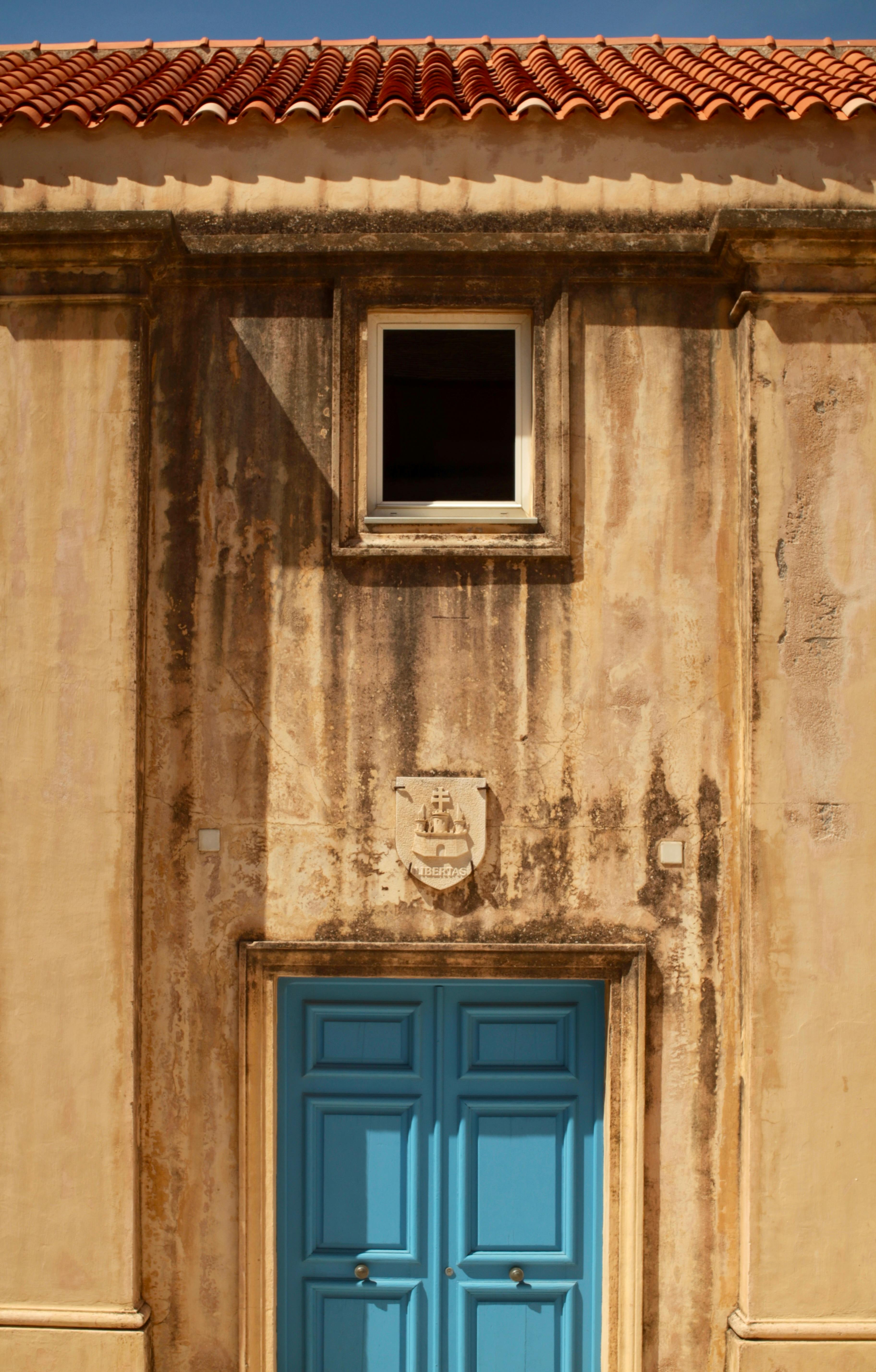 Rustic wall with a striking blue doorway in sunny Bonifacio, Corsica.