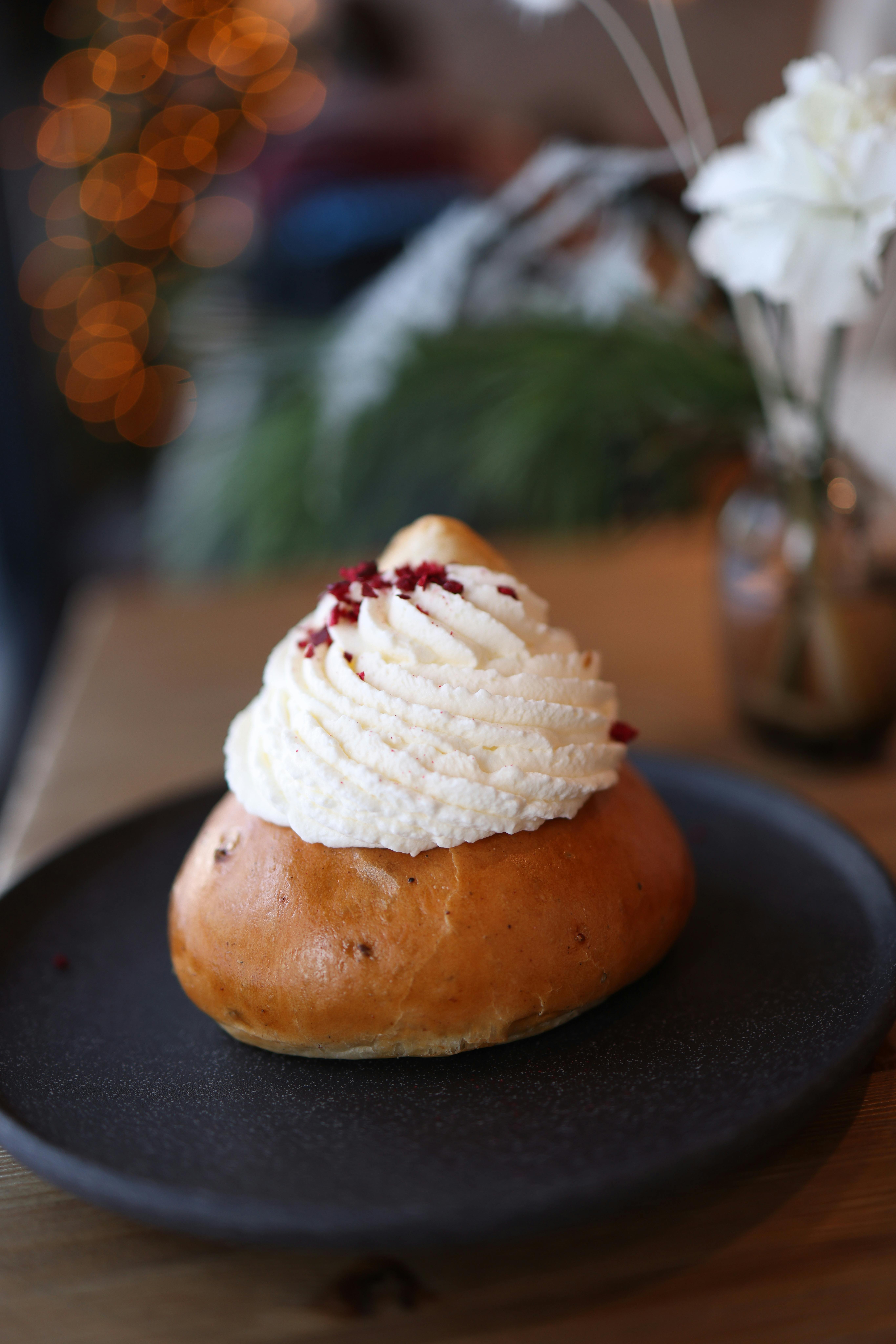 A delicious pastry topped with whipped cream served on a black plate, perfect for dessert lovers.
