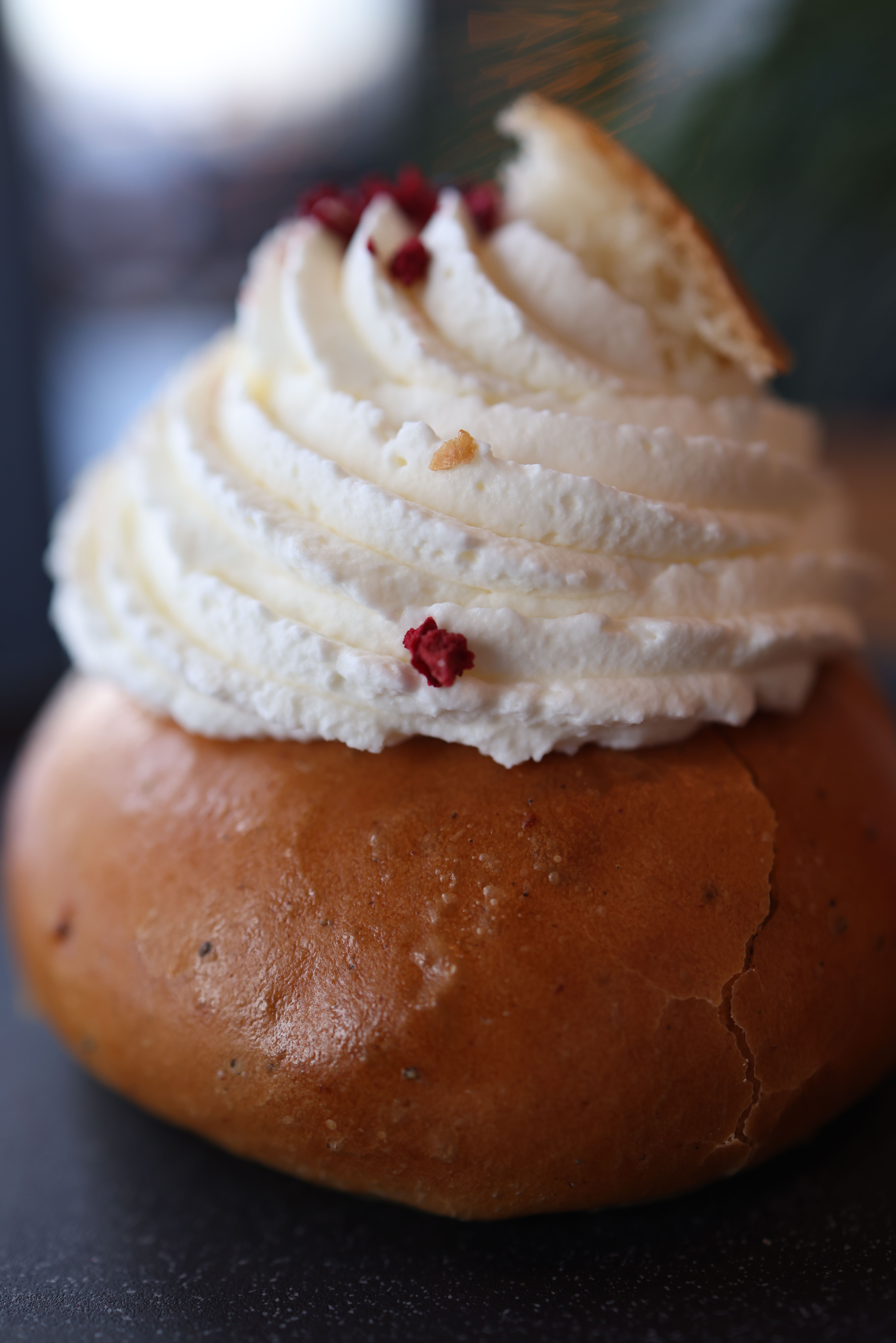A delicious pastry topped with whipped cream and red berries photographed in soft focus.
