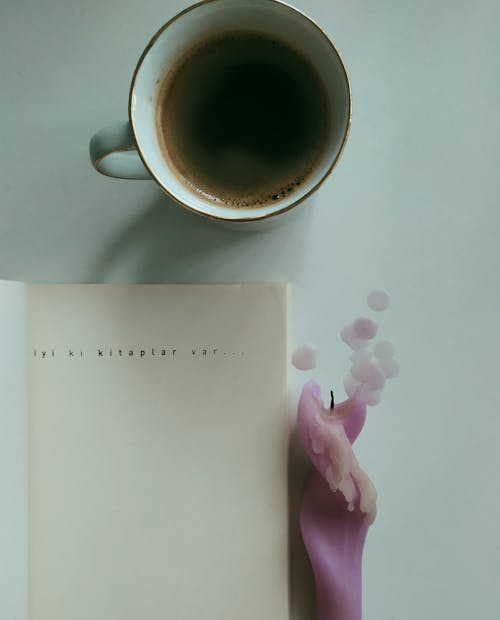 Book and a Candle next to a Cup of Coffee 