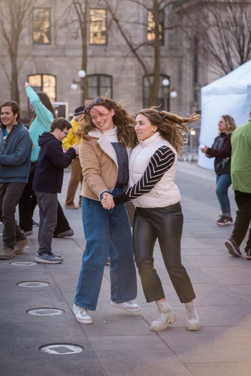 Free Two young women dance joyfully on the streets of Québec City during a vibrant street celebration. Stock Photo