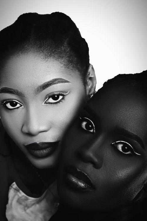 Free Artistic black and white portrait featuring two women with striking white eyeliner makeup Stock Photo