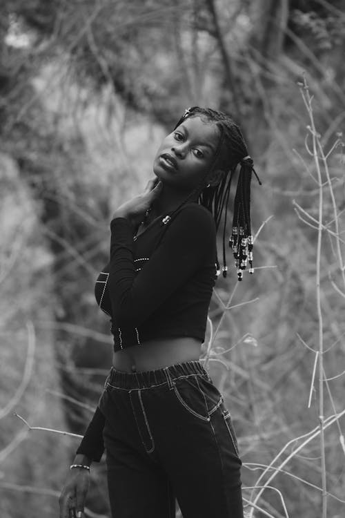 Young Woman with Braided Hair and in a Casual Outfit Posing between Tree Branches