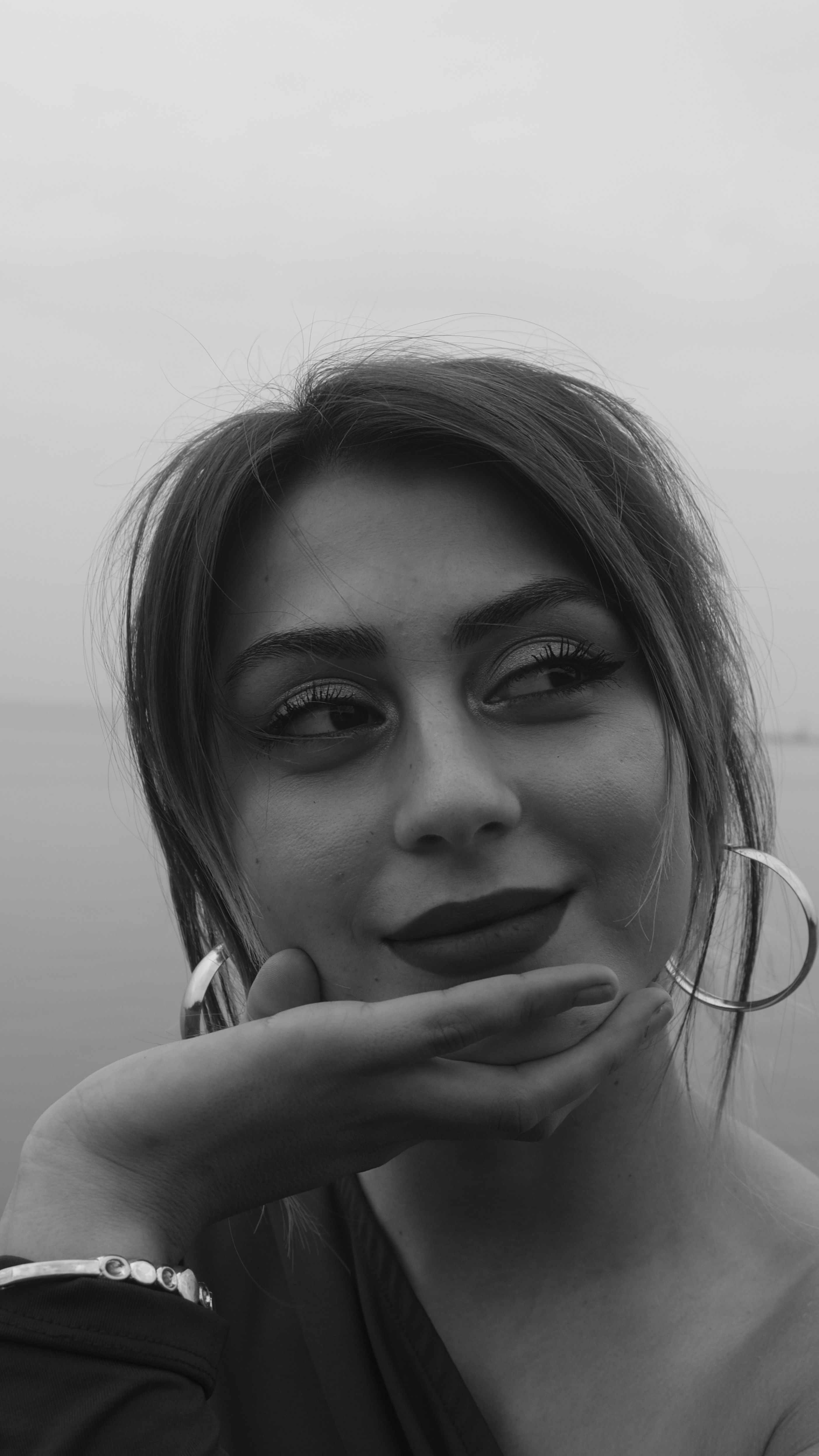 Captivating black and white portrait of a young woman with earrings, showcasing elegance.