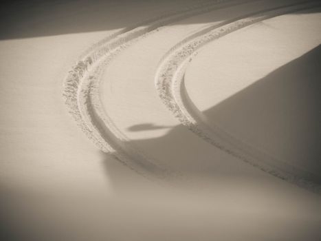Curved tire tracks on fresh snow in Reggio Emilia, Italy during winter.
