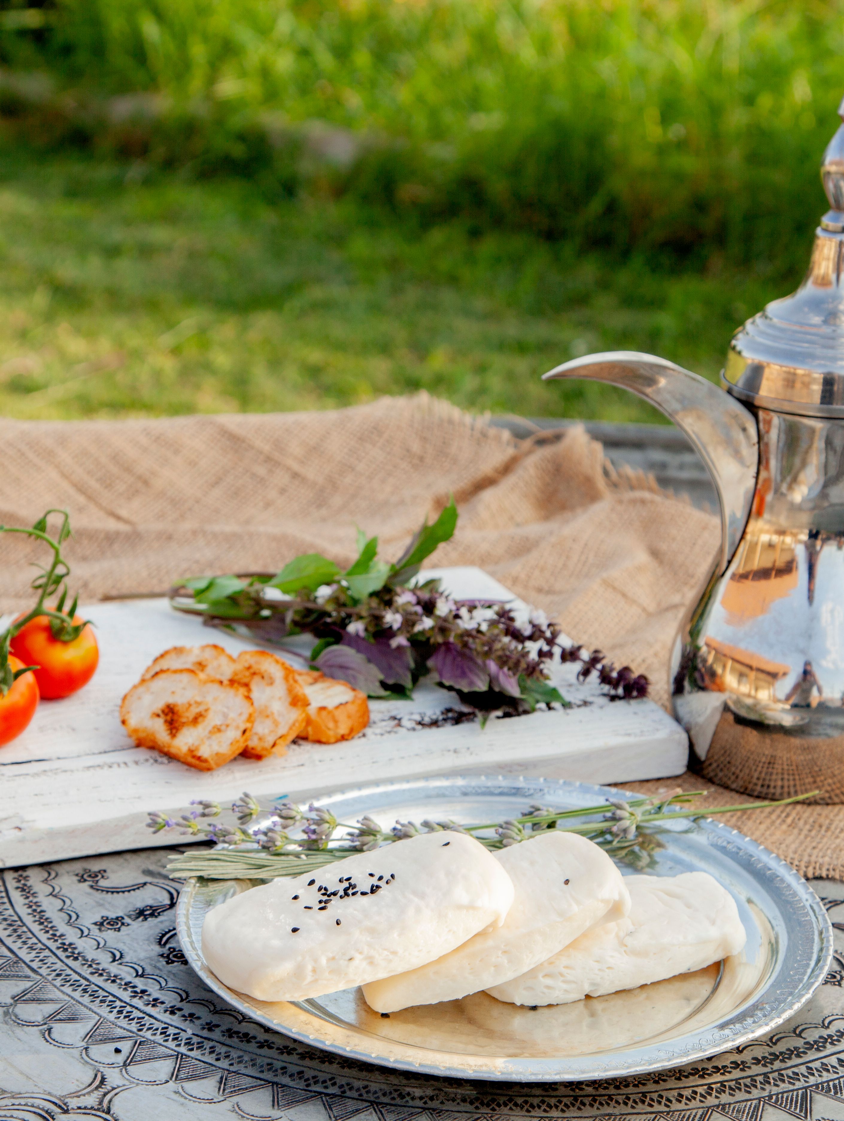 Enjoy a rustic breakfast outdoors with fresh bread, herbs, and tomatoes. Perfect for foodie photography.